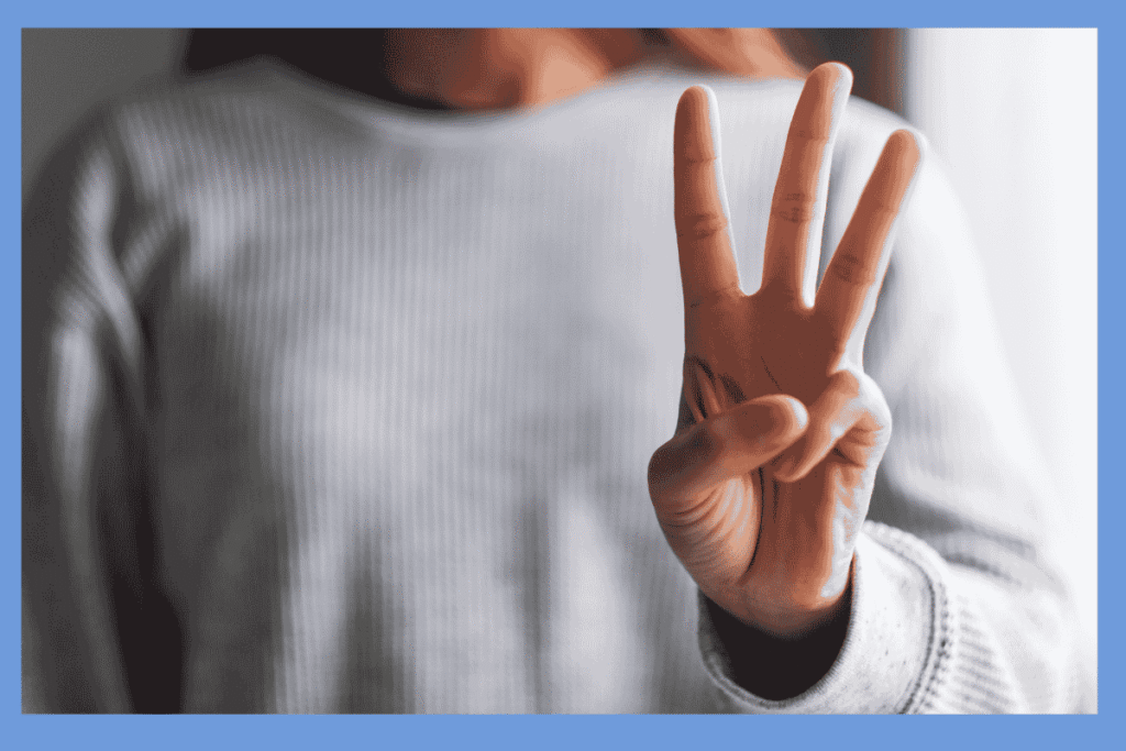 数字の3を示す指を立てた人の手のアップ